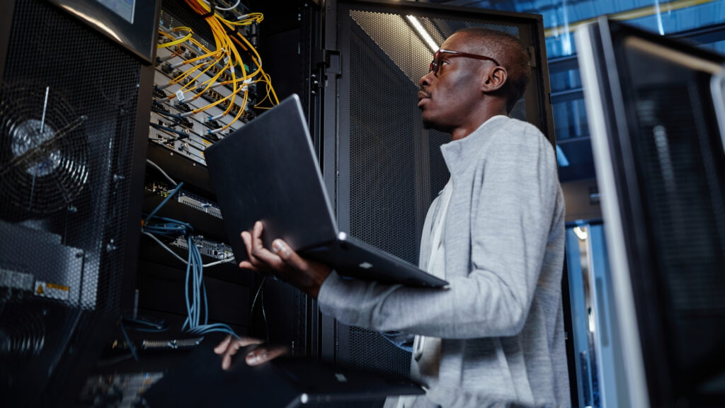 man using laptop while working with servers